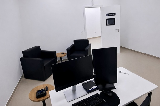 Foto horizontal: sala de atendimento equipada com computadores, poltronas e dispositivos eletrônicos.