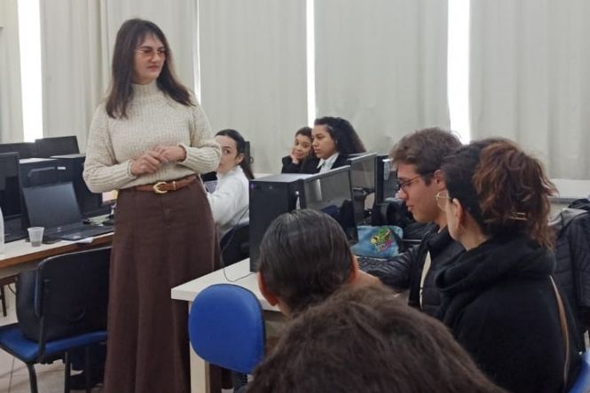 Imagem horizontal mostra servidora do PJSC orientando acadêmicos de direito durante prática de mediação.