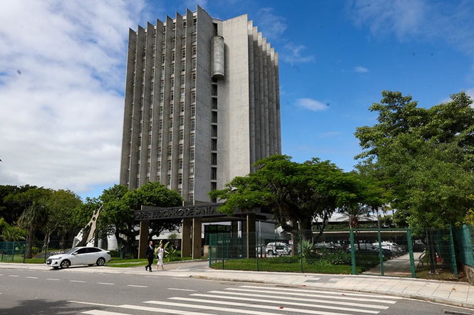 Imagem horizontal mostra prédio do Tribunal de Justiça de Santa Catarina, cercado por árvores, sob céu azul.