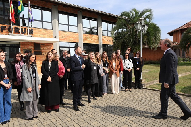 Foto horizontal: presidente do TJSC, desembargador Rubens Schulz, caminha em direção a grupo de pessoas reunido em frente ao Fórum.