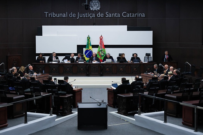 Foto horizontal: sessão no plenário do Tribunal de Justiça de Santa Catarina reúne desembargadores, com bandeiras do Brasil e de Santa Catarina ao centro.