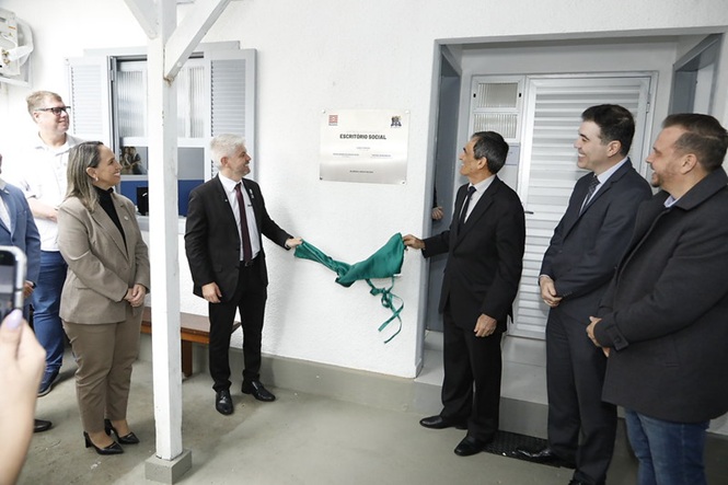 Foto horizontal: autoridades participam do descerramento de placa de um Escritório Social, durante cerimônia de inauguração.