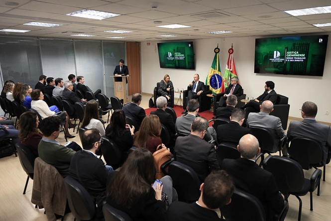 Foto horizontal: presidente do TJSC, des. Rubens Schulz, fala ao microfone durante evento, diante do público e de autoridades.
