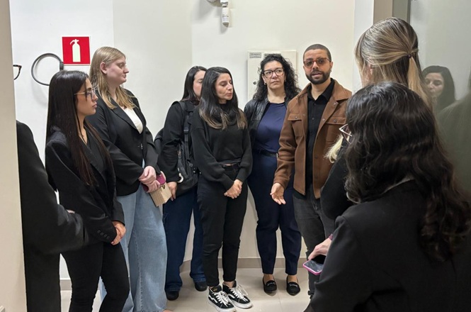 Foto horizontal: grupo de profissionais acompanha explicações durante visita a uma unidade do Poder Judiciário.