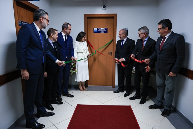 Foto horizontal: autoridades seguram fitas verde e vermelha durante cerimônia de inauguração em corredor institucional.