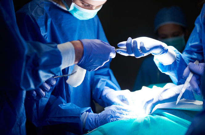 Foto colorida: equipe médica durante cirurgia, centro cirúrgico hospitalar, procedimento de saúde, realizando operação em azul, branco e verde-claro